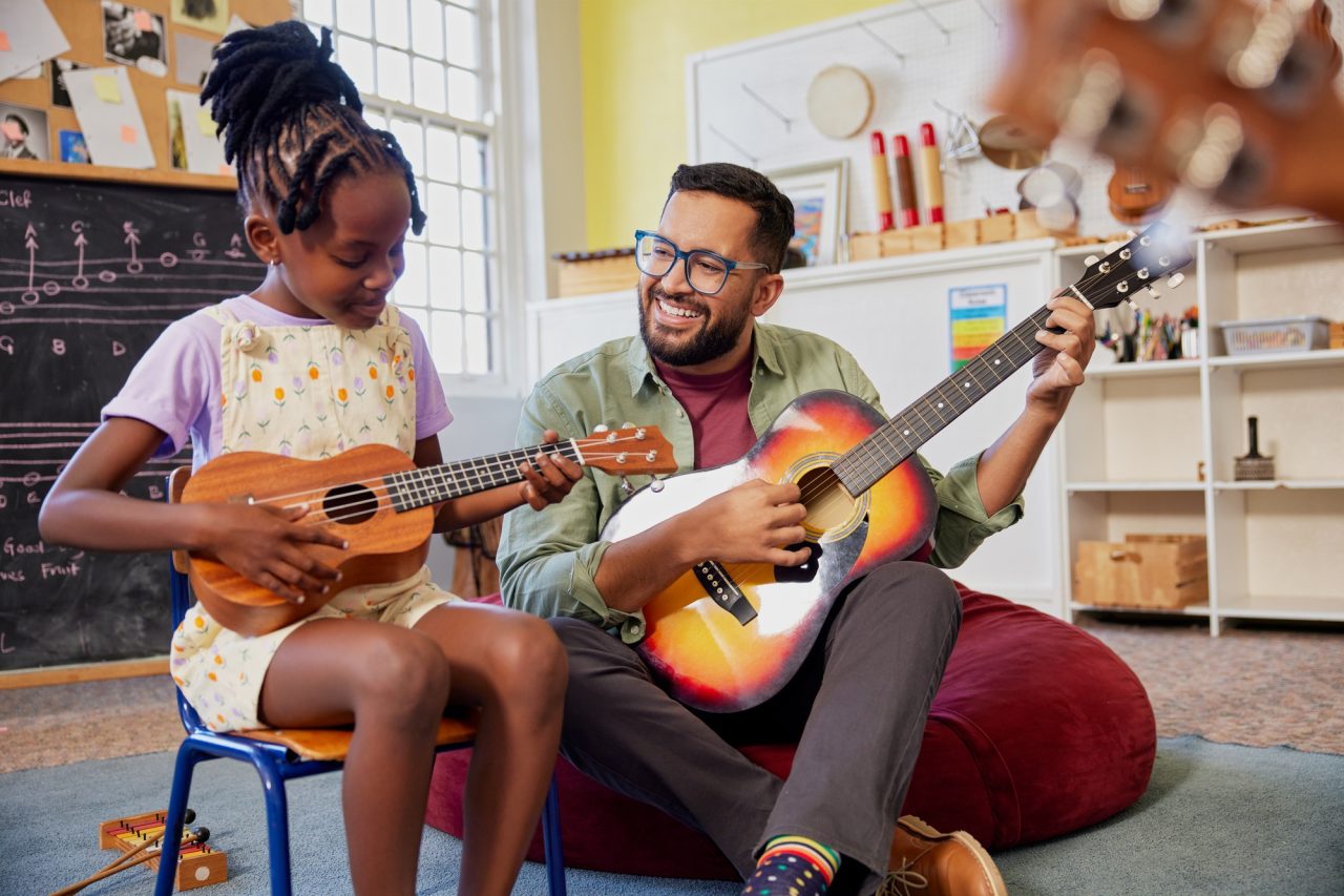 Profesor de guitarra enseñando a su alumna en casa durante una clase personalizada en Lima.